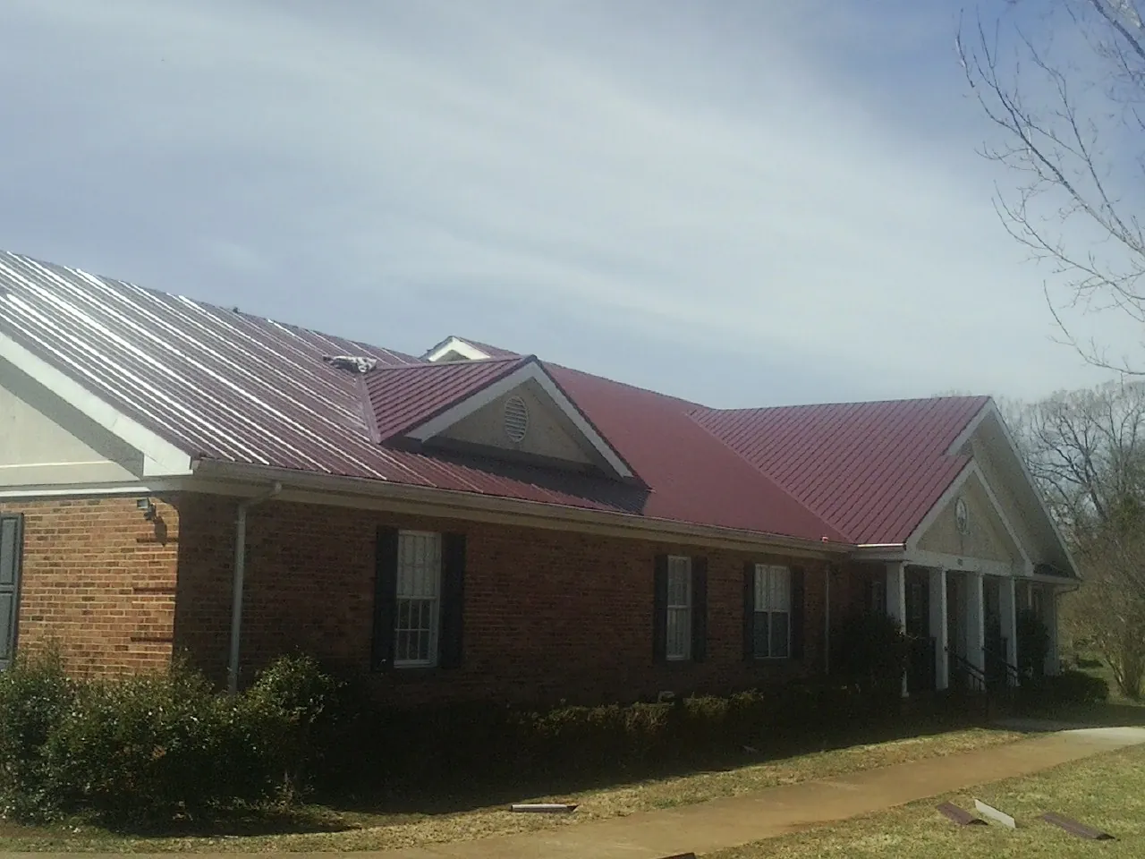 Red metal roof with gabled entries on a long brick building in Slater