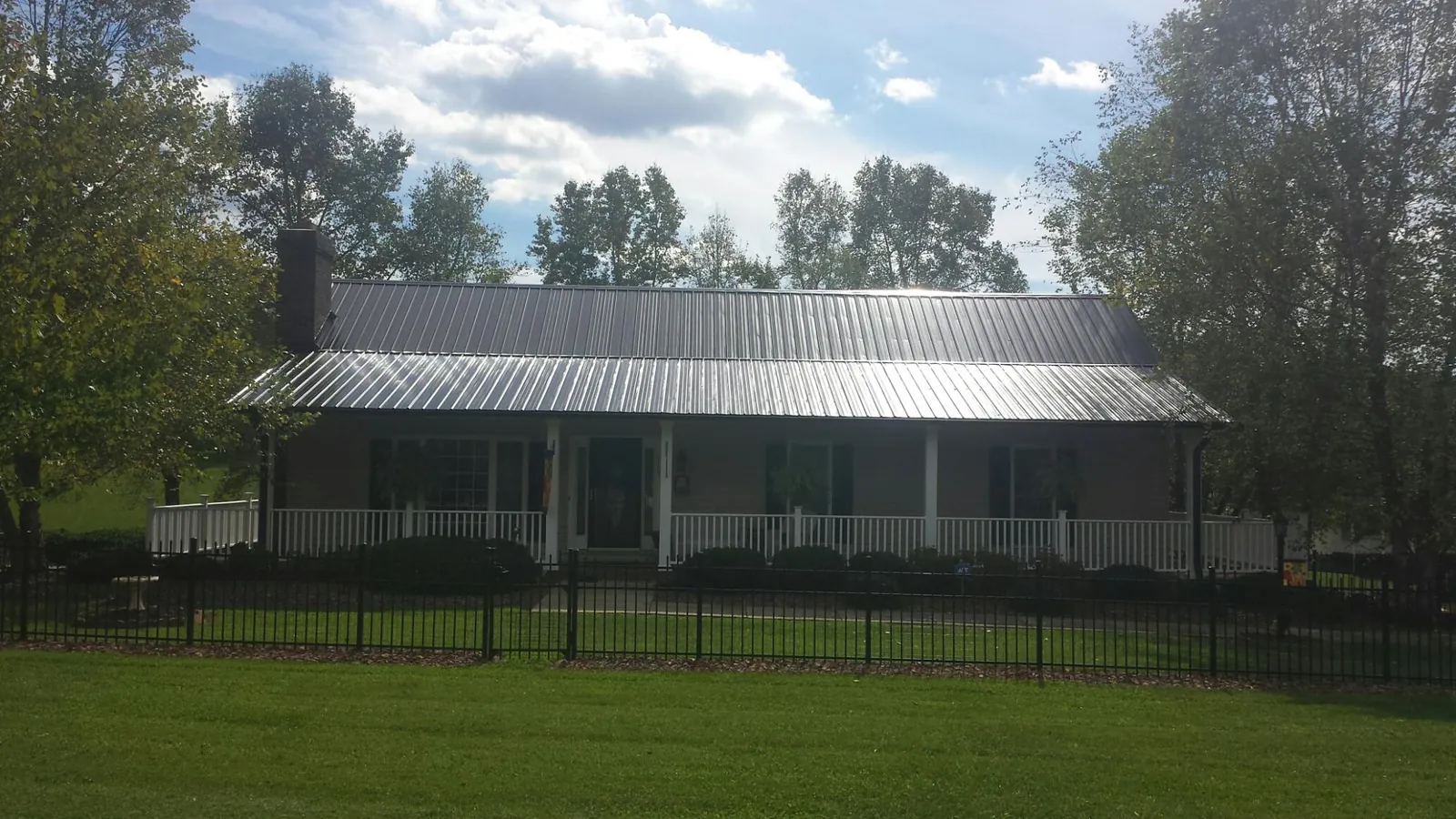 Gray metal roof on a brick ranch with a full width front porch — Gutter Guard Installation work by our crew in Slater