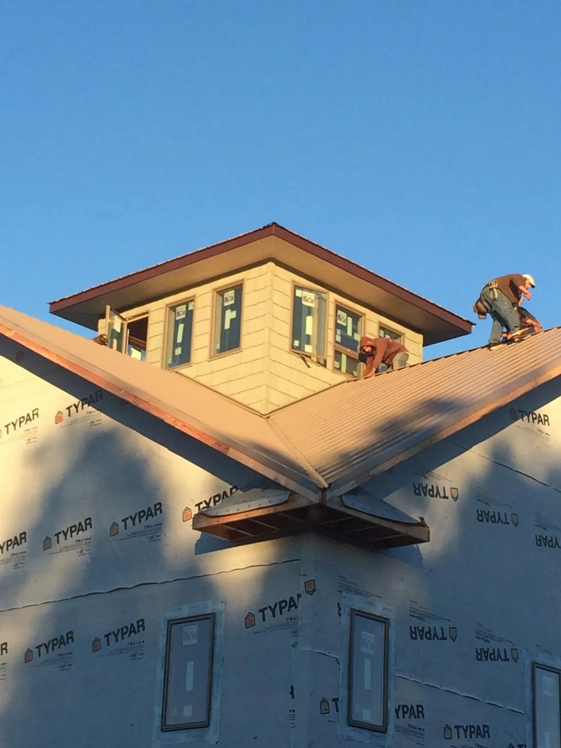 Roofers working around a rooftop cupola on a new metal roof at sunset — Roof Waterproofing in Slater by Roofing Brothers